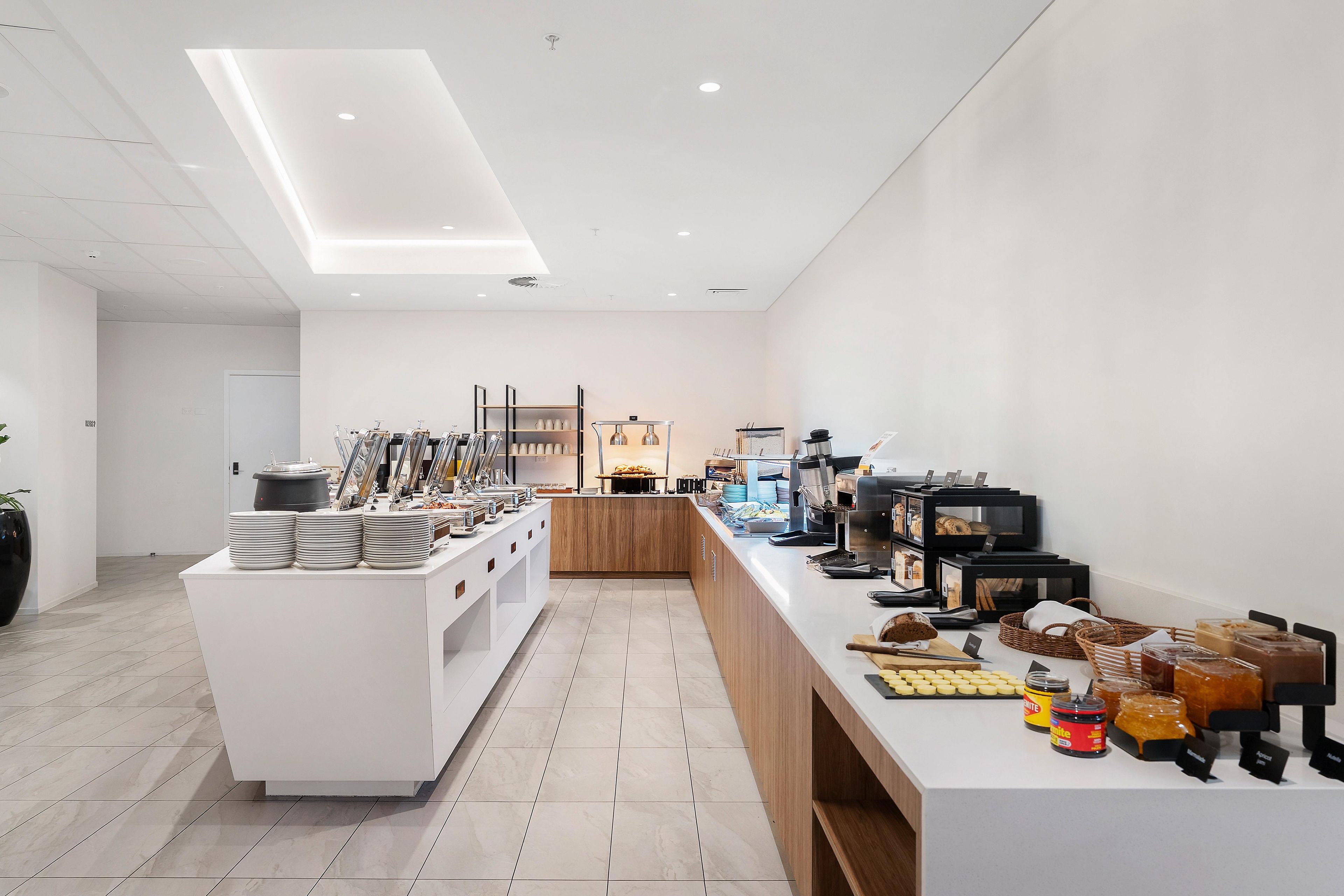 L’intérieur d’un café moderne présente un long comptoir, des machines à café et une variété de produits alimentaires exposés.
