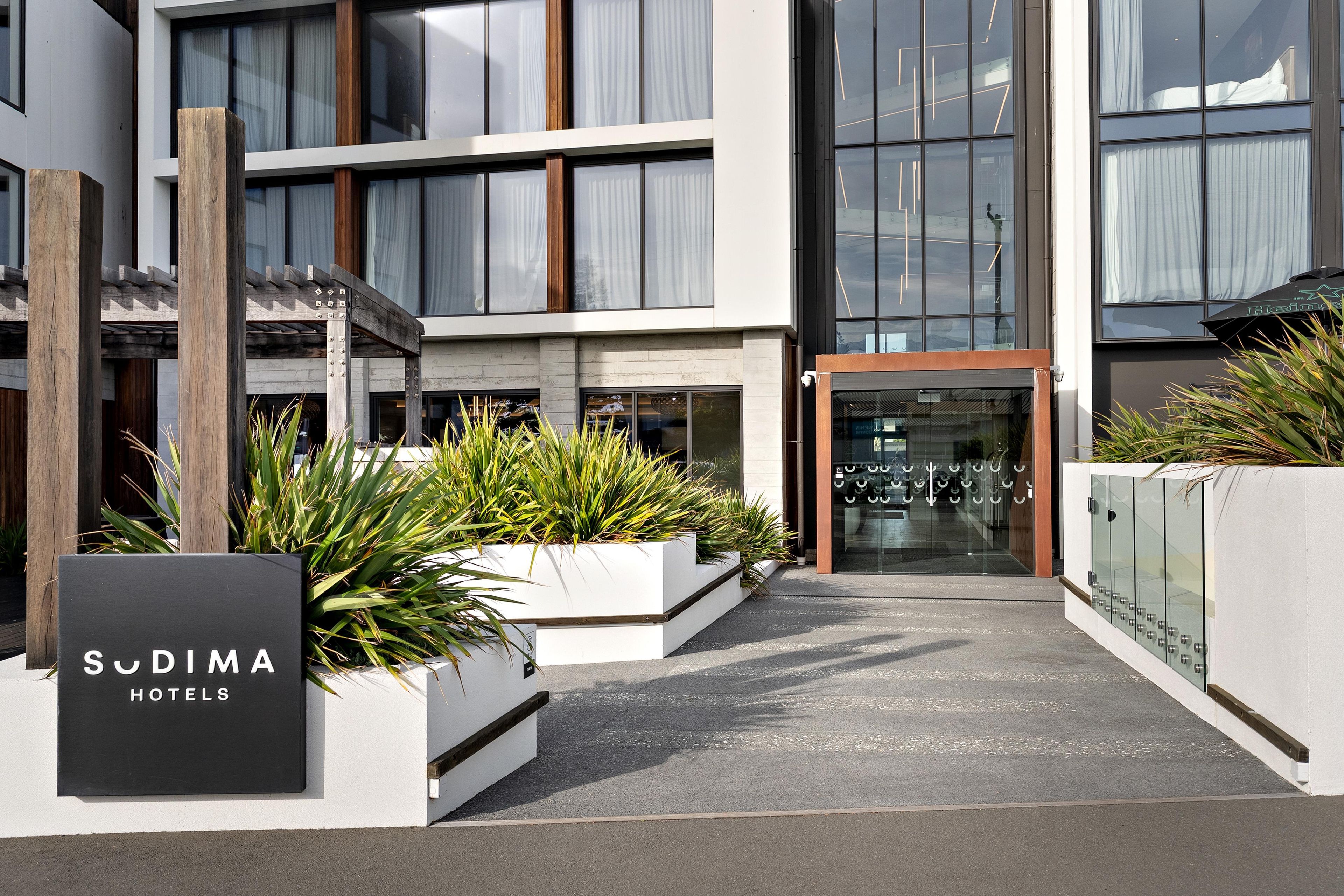 A modern hotel entrance with a sign reading 'Sudima Hotels'.