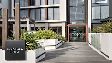 A modern hotel entrance with a sign reading 'Sudima Hotels'.