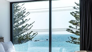 Une chambre avec une grande fenêtre donnant sur la mer, un lit et une chaise.