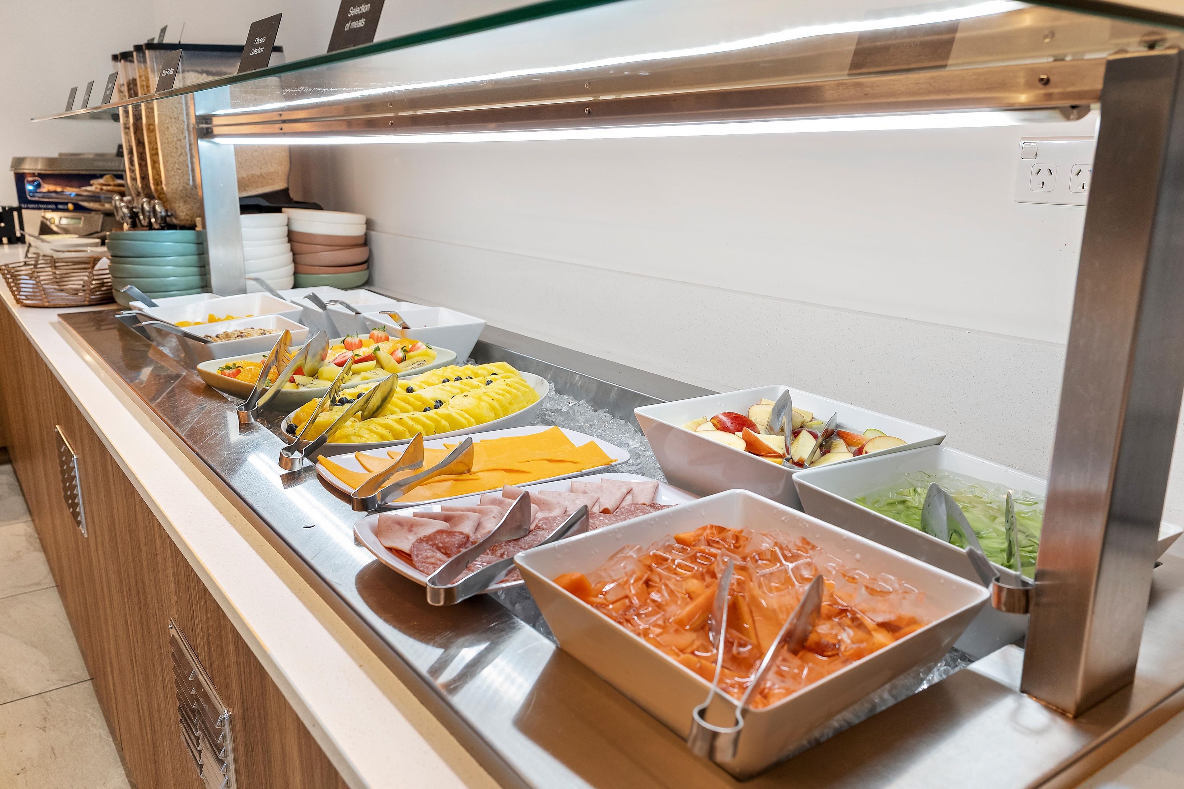 A buffet with various food options including fruits, cheeses, and meats.
