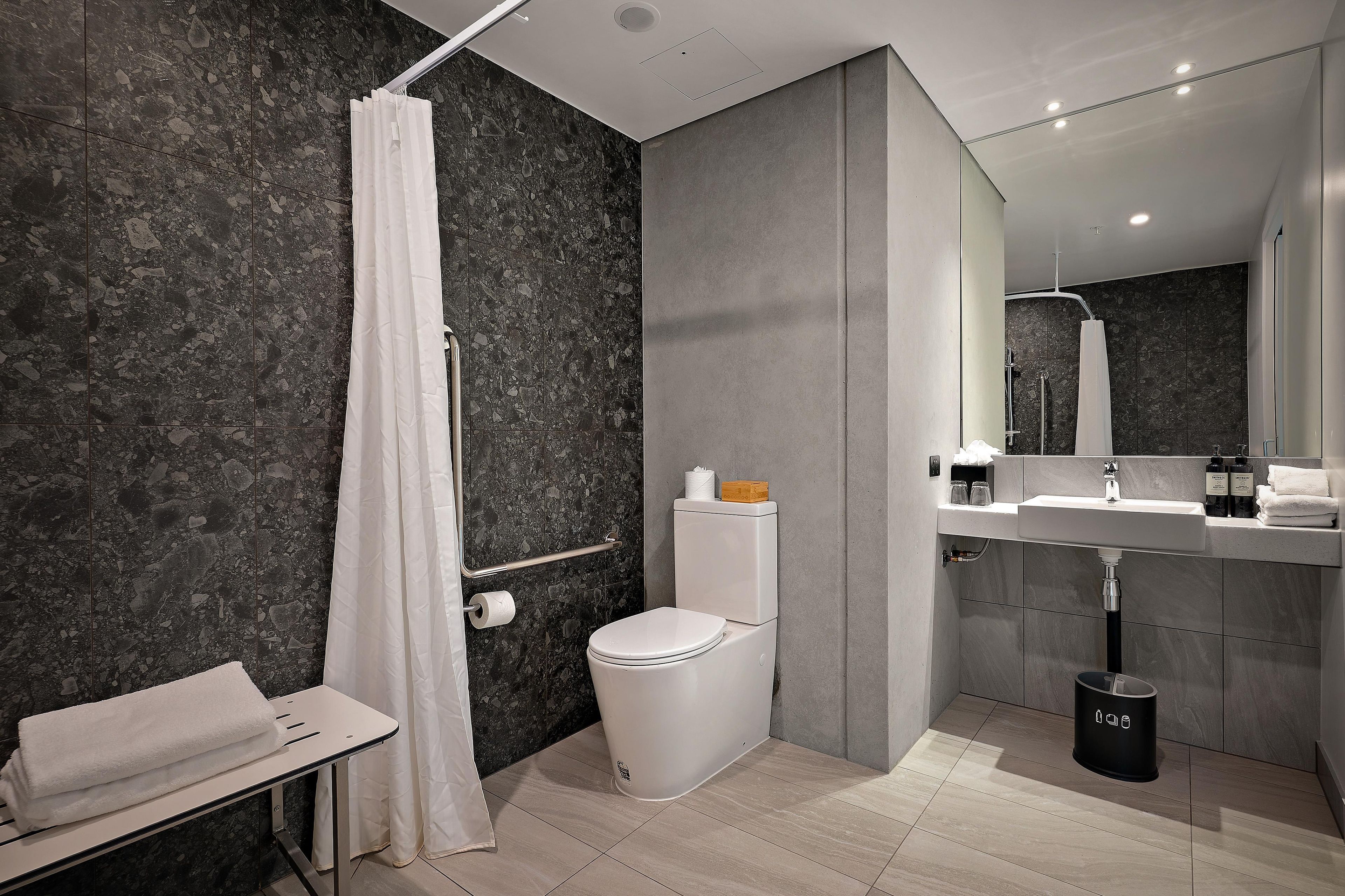 Un baño moderno con ducha, inodoro, lavabo y toallero.