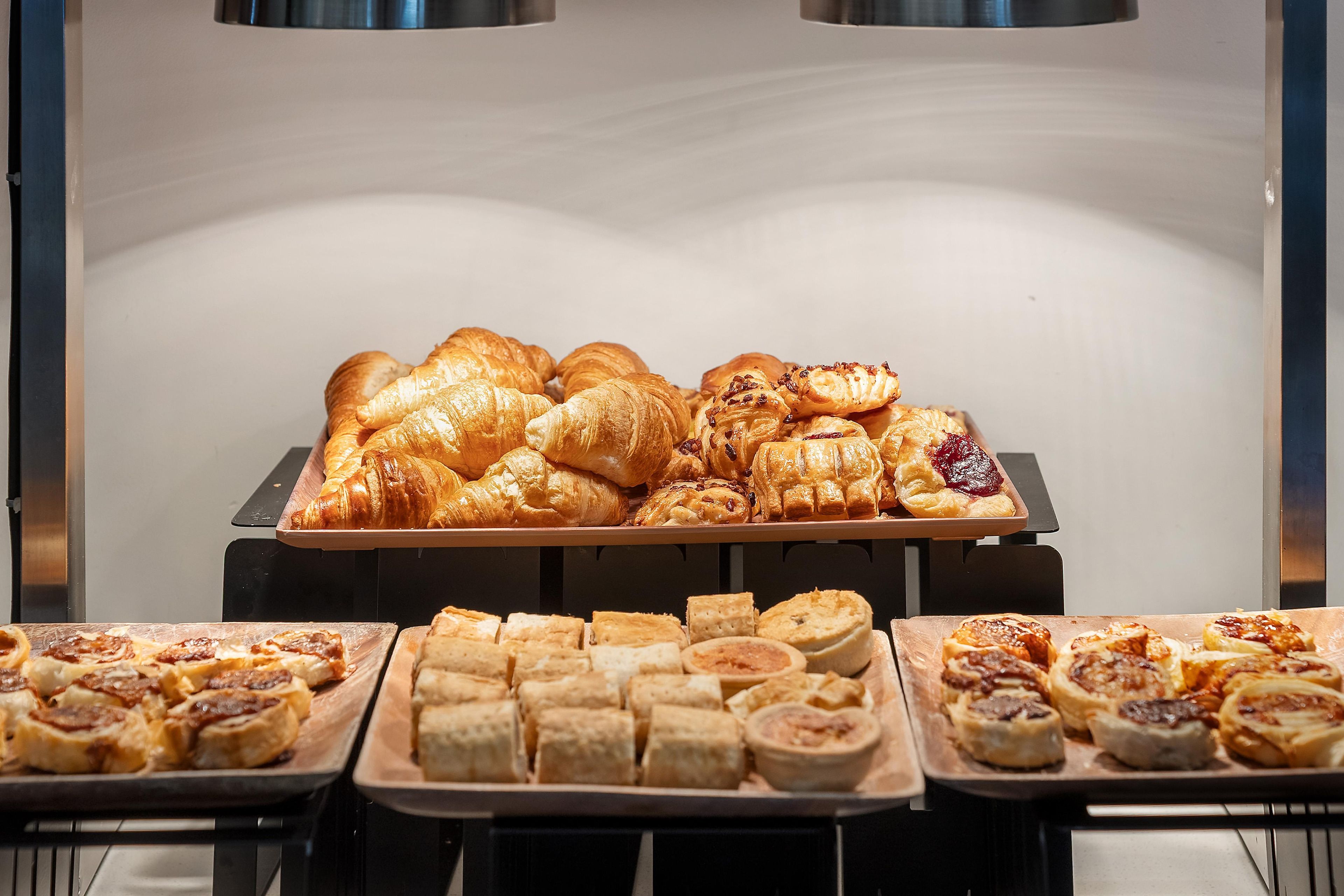A variety of baked goods displayed on trays in a commercial setting.