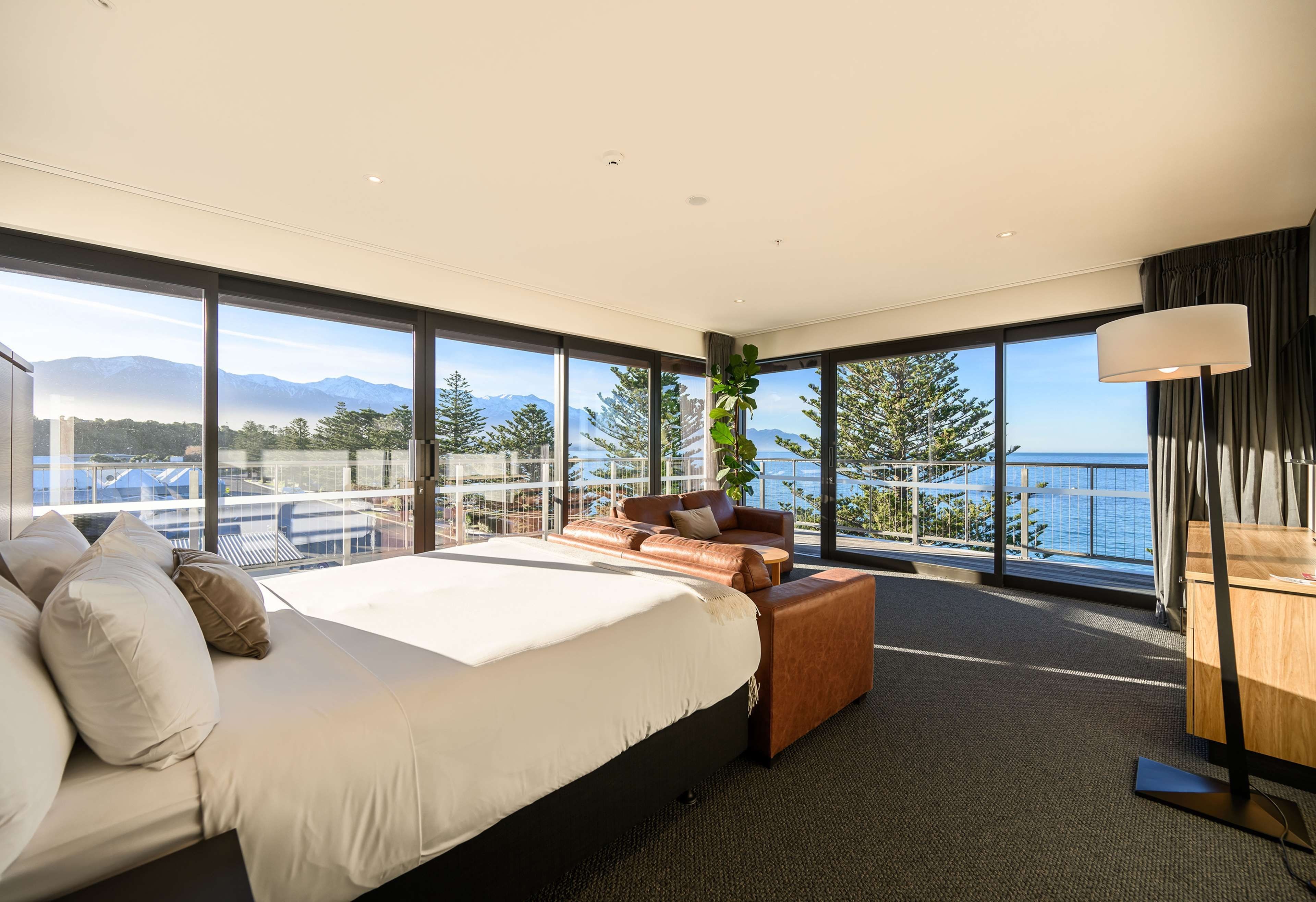 Habitación de hotel moderna con una cama grande, un espacio para sentarse y vista al mar.