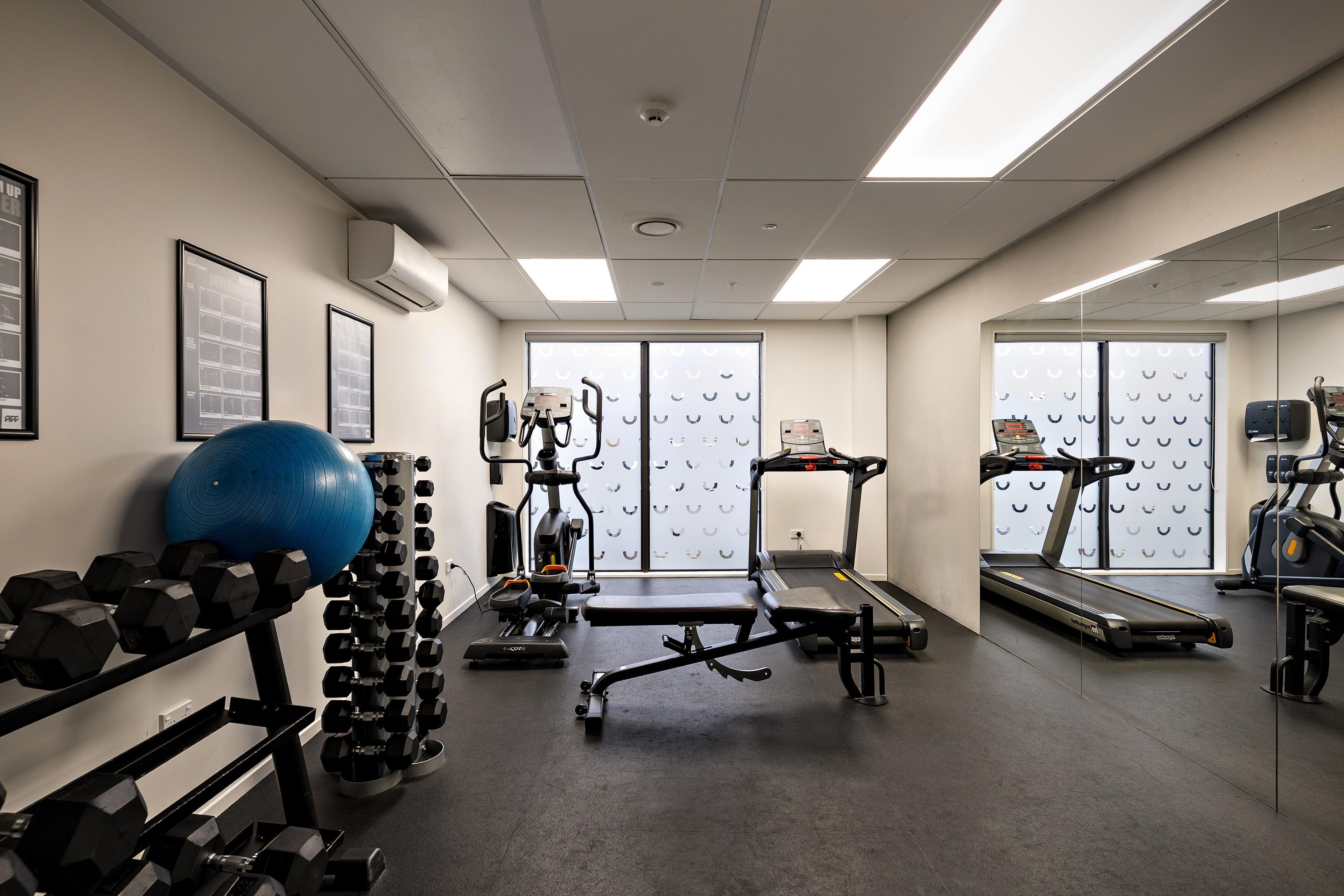 A gym with exercise equipment, including treadmills, a rowing machine, and dumbbells.