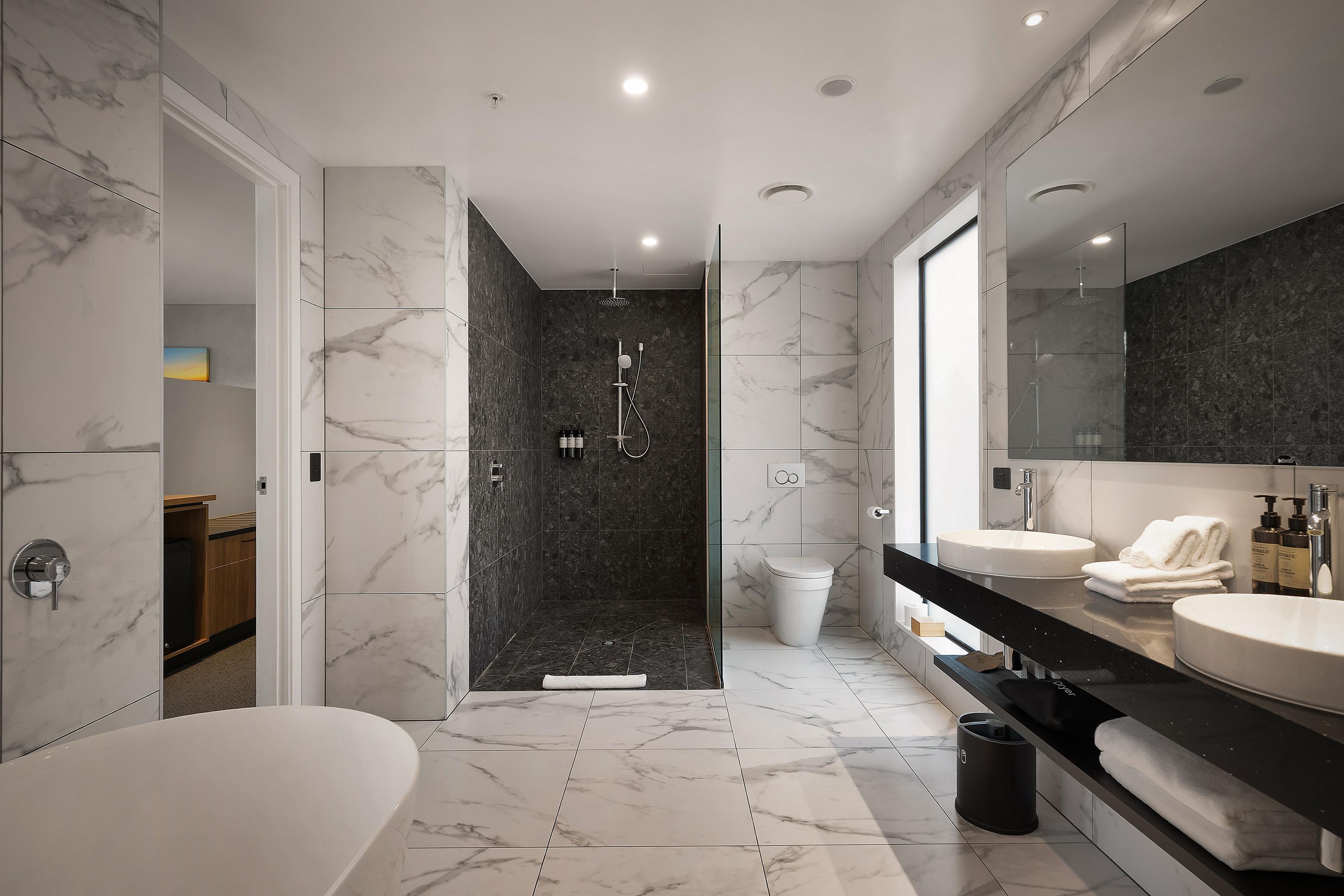 Un baño moderno con bañera, ducha y tocador con un espejo grande.