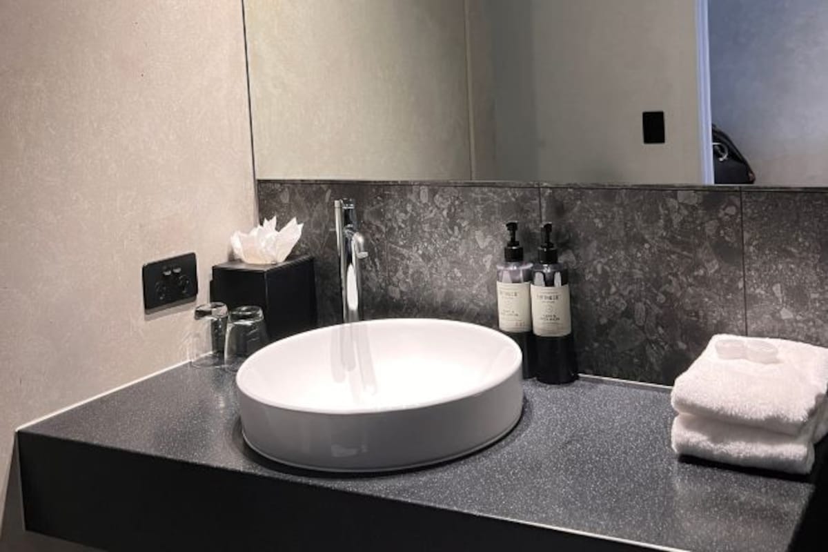 Un baño moderno con un lavabo redondo, un espejo y un perchero para toallas.