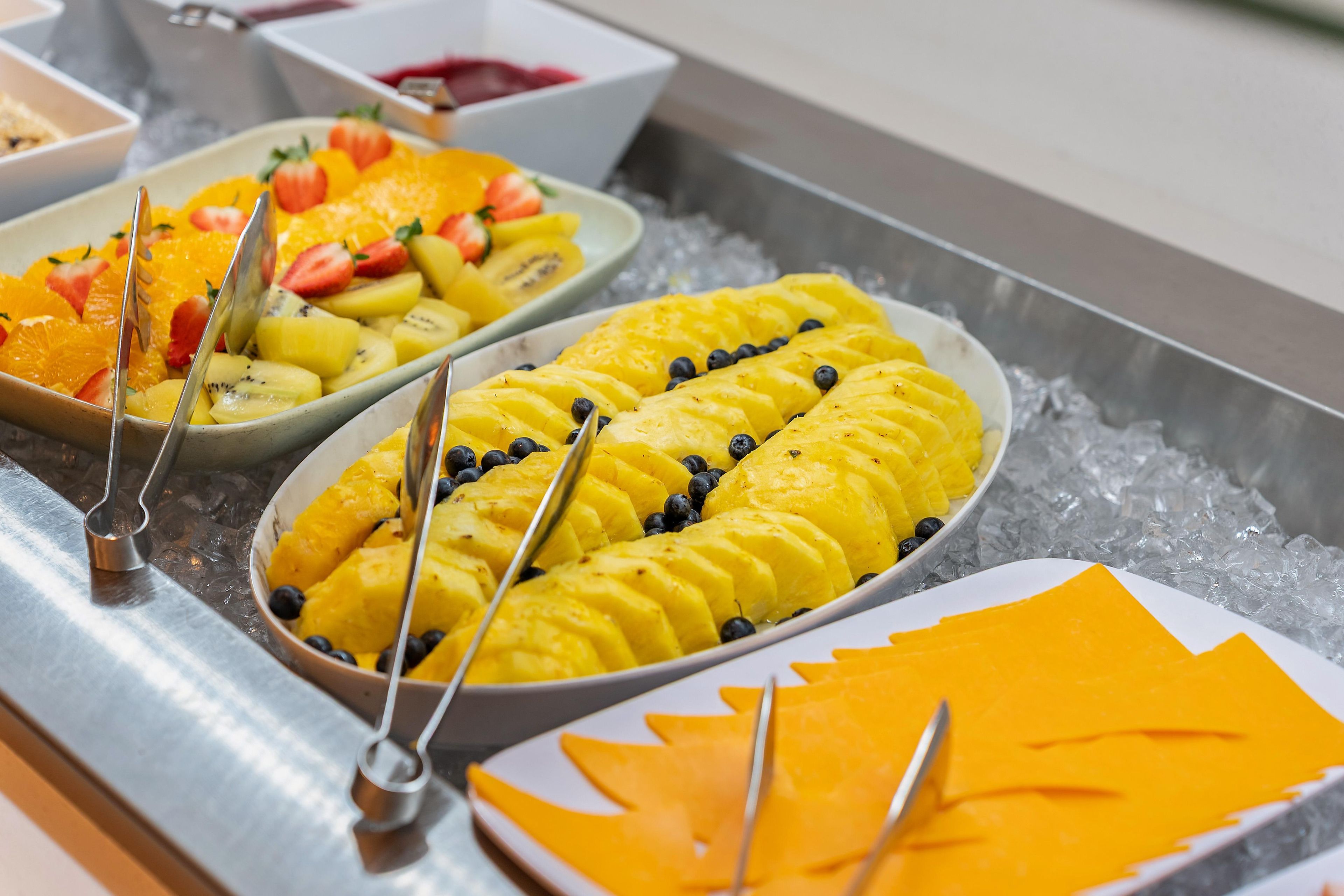 Un bufé con diversas frutas y una bandeja de quesos.