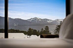 Vista de la montaña desde una ventana, con una cama en primer plano.