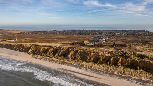 An aerial view of a coastal area with a beach, cliffs, and a cluster of buildings with a flat roof design. - Lovingly designed 62m² apartment offers space for 3 people on the 1st floor. - (Kampen (Sylt))