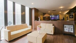 A modern hotel lobby with a sofa, a coffee table, and a TV. - Best Hotel (Surabaya)