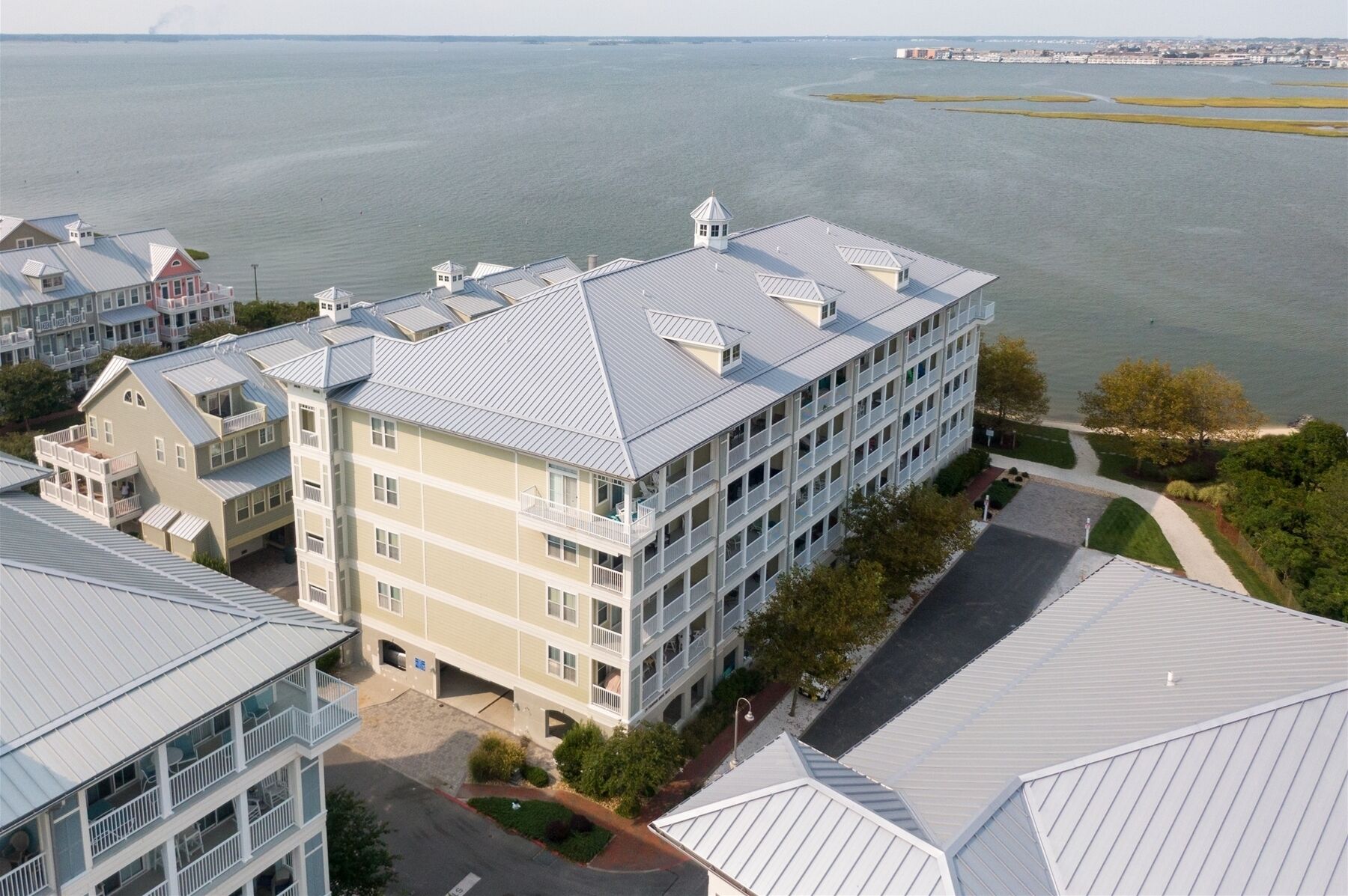 A multi-story hotel with a flat roof, large windows, and a view of the water.