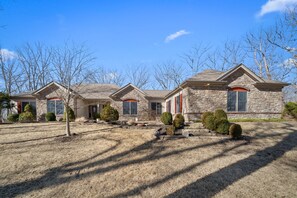 A stone house with a well-maintained lawn and a clear blue sky. - Luxe Innsbrook Resort Home - Lakes/Golf/Trails (Wright City)