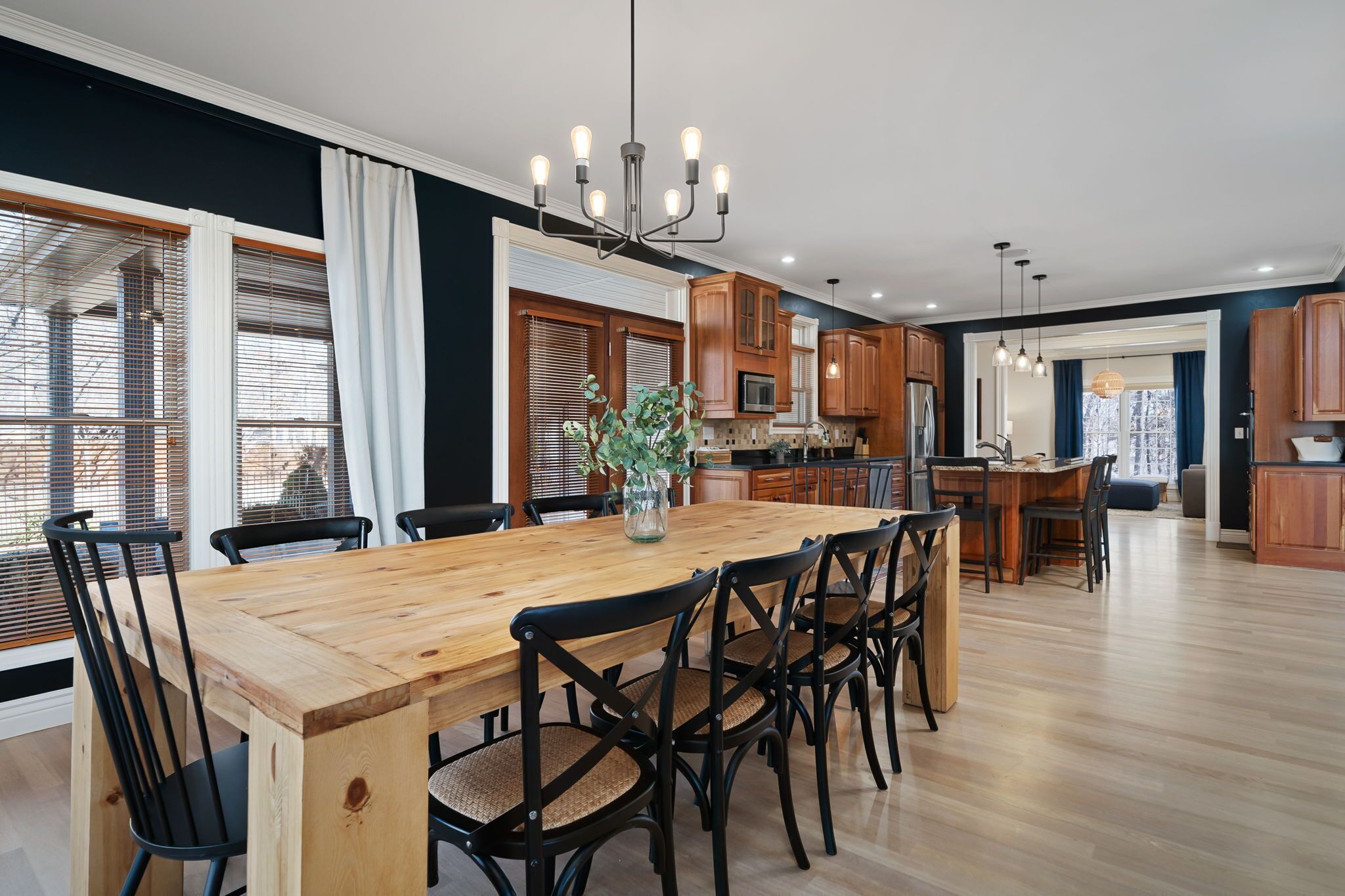A spacious kitchen with wooden cabinets, a central island, and a dining area with a wooden table and chairs.
