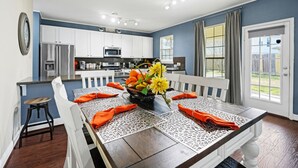 A modern kitchen with white cabinets, a microwave, and a dining area with a table set for four.