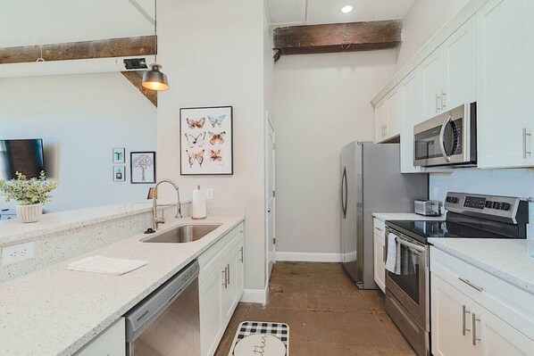 A modern kitchen with white cabinets, stainless steel appliances, and a granite countertop.