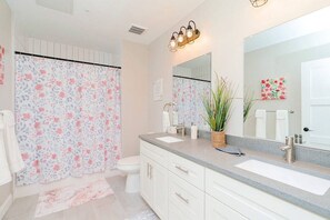 Ein Badezimmer mit Duschvorhang, Toilette, Waschbecken und Spiegel.