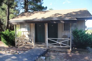 A small building with a porch, a green door, and a number 19 on the door.