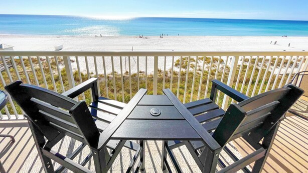 Una terraza de madera con una mesa y sillas que da a una playa.
