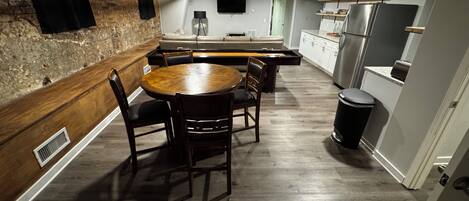 Una cocina compacta con comedor, piso de madera y pared de ladrillo.