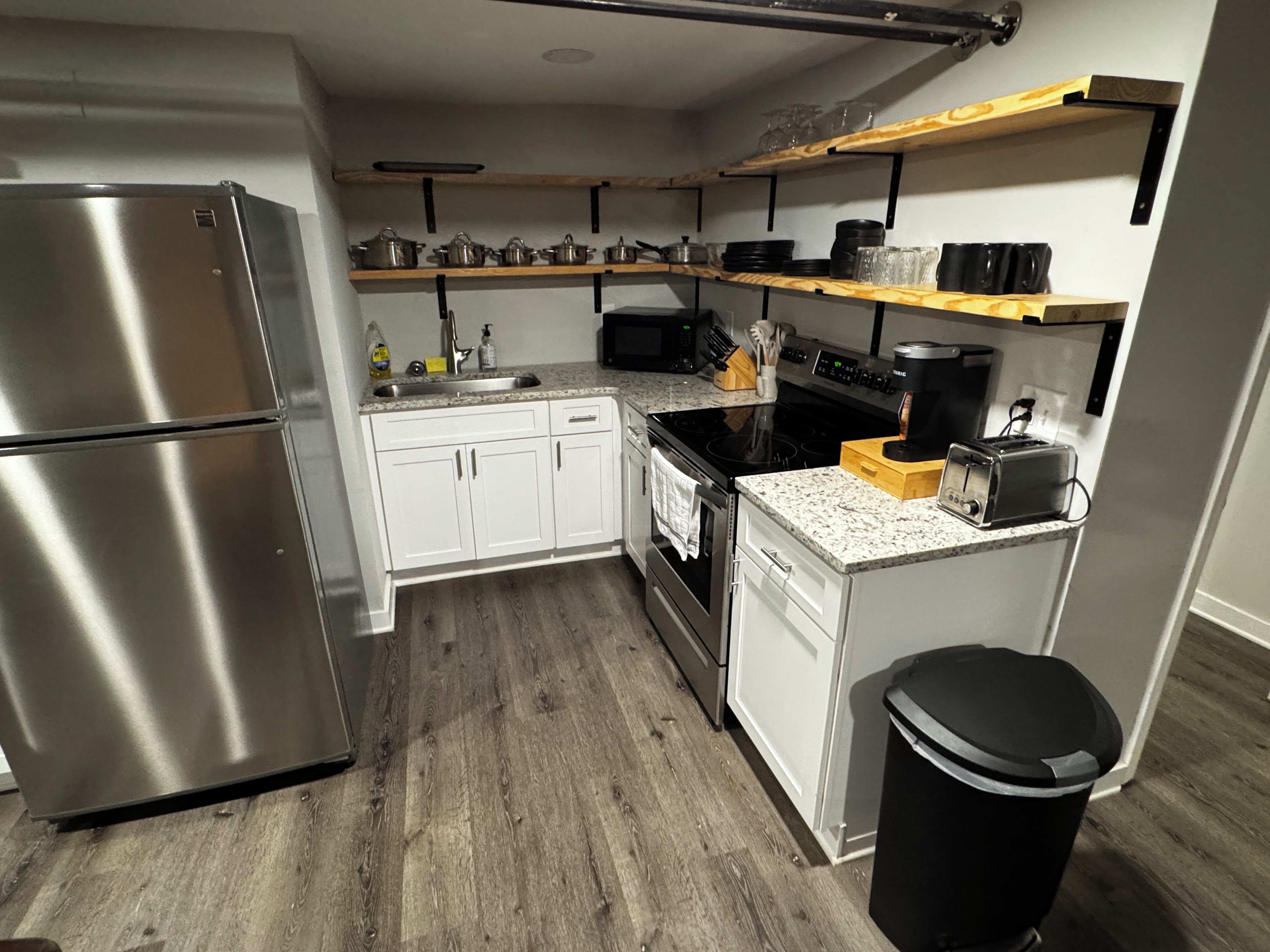 A compact kitchen with a stainless steel refrigerator, white cabinets, a microwave, and a toaster.