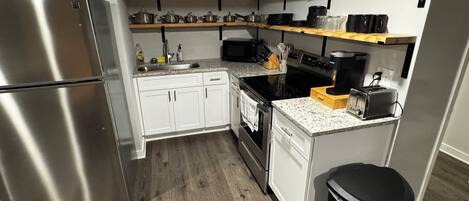 A compact kitchen with a stainless steel refrigerator, white cabinets, a microwave, and a toaster.