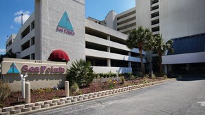 A multi-story parking garage with a sign for "SeaPoint" and a red umbrella. - Oceanfront Condo-large, corner balcony, enclosed pool in popular Cherry Grove Beach (North Myrtle Beach)