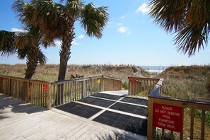 A wooden deck with a warning sign about not removing lounge chairs from the deck.