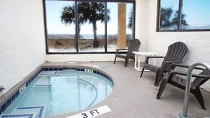 A 3 FT hot tub with a view of the beach, surrounded by chairs and a table. - Oceanfront Condo-large, corner balcony, enclosed pool in popular Cherry Grove Beach (North Myrtle Beach)