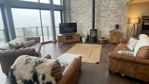 A spacious living room with leather sofas, a flat-screen TV, a stone wall, and a fireplace. - Pendle View Sleeps 8 with Hot Tub (Longridge, Preston)