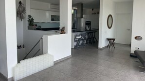 Eine moderne Küche mit weißen Schränken, einer zentralen Kochinsel und einem Essbereich mit Barhocker.