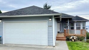 Une maison de plain-pied avec un garage, le numéro « 680 » peint sur la porte du garage, et un petit porche d’où l’on peut admirer la vue sur l’eau.