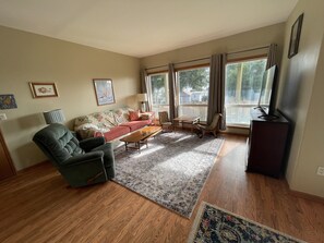 A living room with a sofa, armchairs, a coffee table, and a TV. - Large comfortable home with stunning views (Astoria)