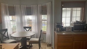 Une cuisine équipée d’une table ronde, de chaises, d’une machine à café, d’un grille-pain et d’un four à micro-ondes.