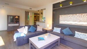 A modern living room with a grey sofa set, a coffee table, and a large abstract wall art piece.