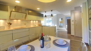 A modern kitchen with white cabinets, a dining table set with plates, glasses, and a bottle of wine.