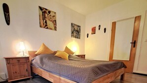 Ein Schlafzimmer mit einem hölzernen Bett, einem Nachttisch, einer Lampe und einer Tür.