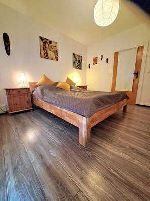 Una camera da letto con un letto di legno, un comodino, una lampada e una porta.