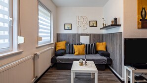 Ein Wohnzimmer mit einer Couch, einem Couchtisch, einem Fernseher und einer Heizung.
