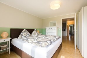 A bedroom with a bed, bedside table, dresser, and a mirror.
