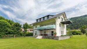 Een huis met twee verdiepingen, een balkon, een stenen fundering en een gazon.