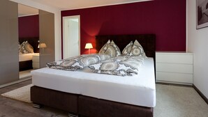 Een slaapkamer met een bed, nachtkastjes, een spiegel en een deur.