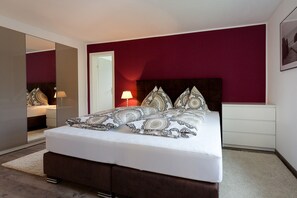 A bedroom with a bed, bedside tables, a mirror, and a door.