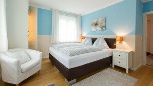 A bedroom with a bed, bedside tables, a chair, and a window with curtains. - Apartment 'Villa Müller Rotfuchs' with Lake View, Shared Garden and Wi-Fi (Ossiach)