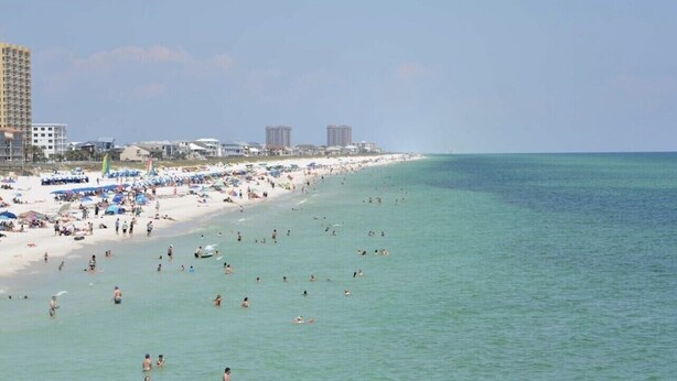 A beach with people swimming and sunbathing, and buildings in the background. - 2 bd 1 bath home - King bed - close to beaches&downtown - backyard with firepit (Pensacola)