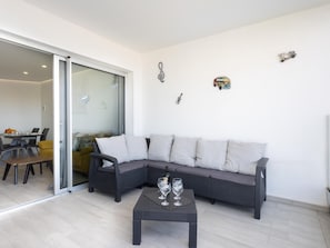 A modern living room with a sectional sofa, a glass door leading to a dining area, and decorative wall art.