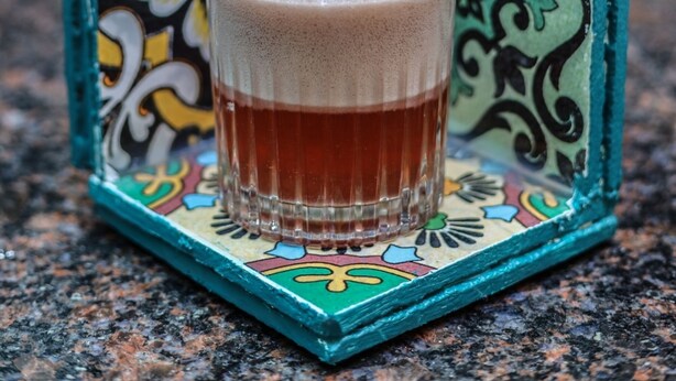 A glass of beverage on a colorful tile coaster with a book titled "Cuba Habana" in the background. - Quba by Montraj Pattaya, previously The Quba Hotel Pattaya (Pattaya)