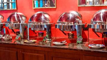 A buffet setup with multiple food service stations, each with a dome cover and a small sign indicating the type of food served.