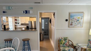 Una cocina moderna con un refrigerador de acero inoxidable, una barra con taburetes y una mesa de comedor con sillas.