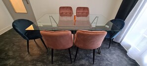 Une table de conférence avec un plateau en verre et quatre chaises, deux de chaque côté.